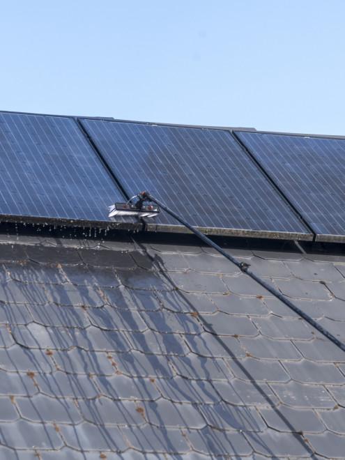 Close-up of dusty, pollen-coated rooftop solar panels on a Clovis home before cleaning.