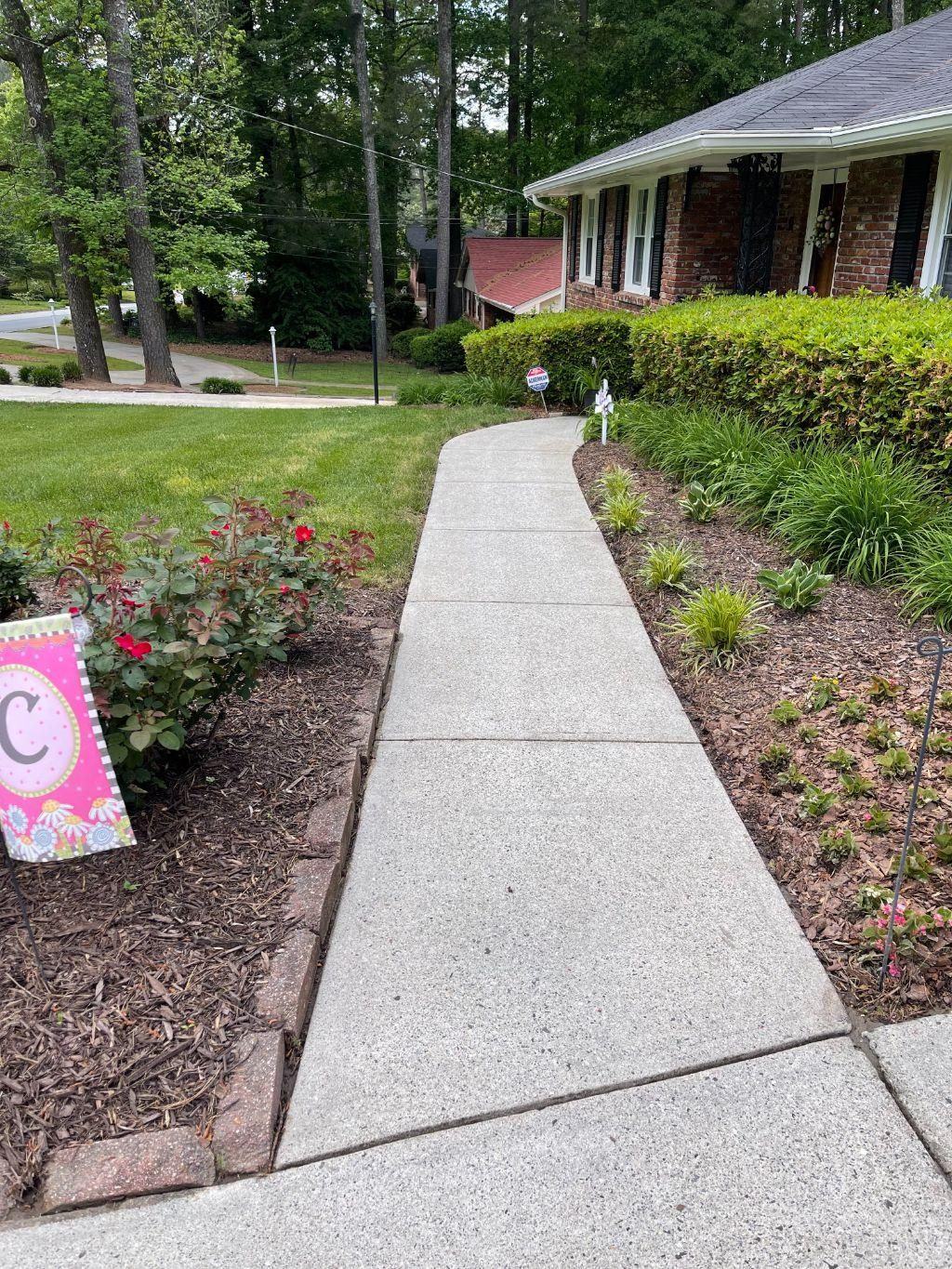 Clean residential walkway leading to a brick home with tidy landscaping.