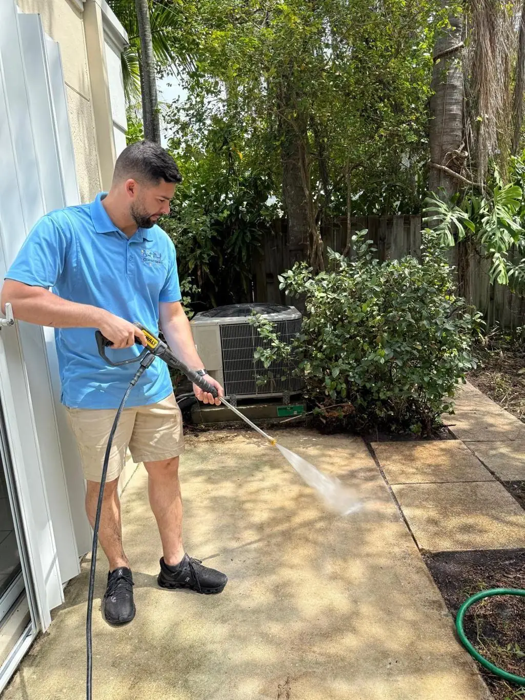 Valley Concrete technician pressure washing a backyard concrete patio.