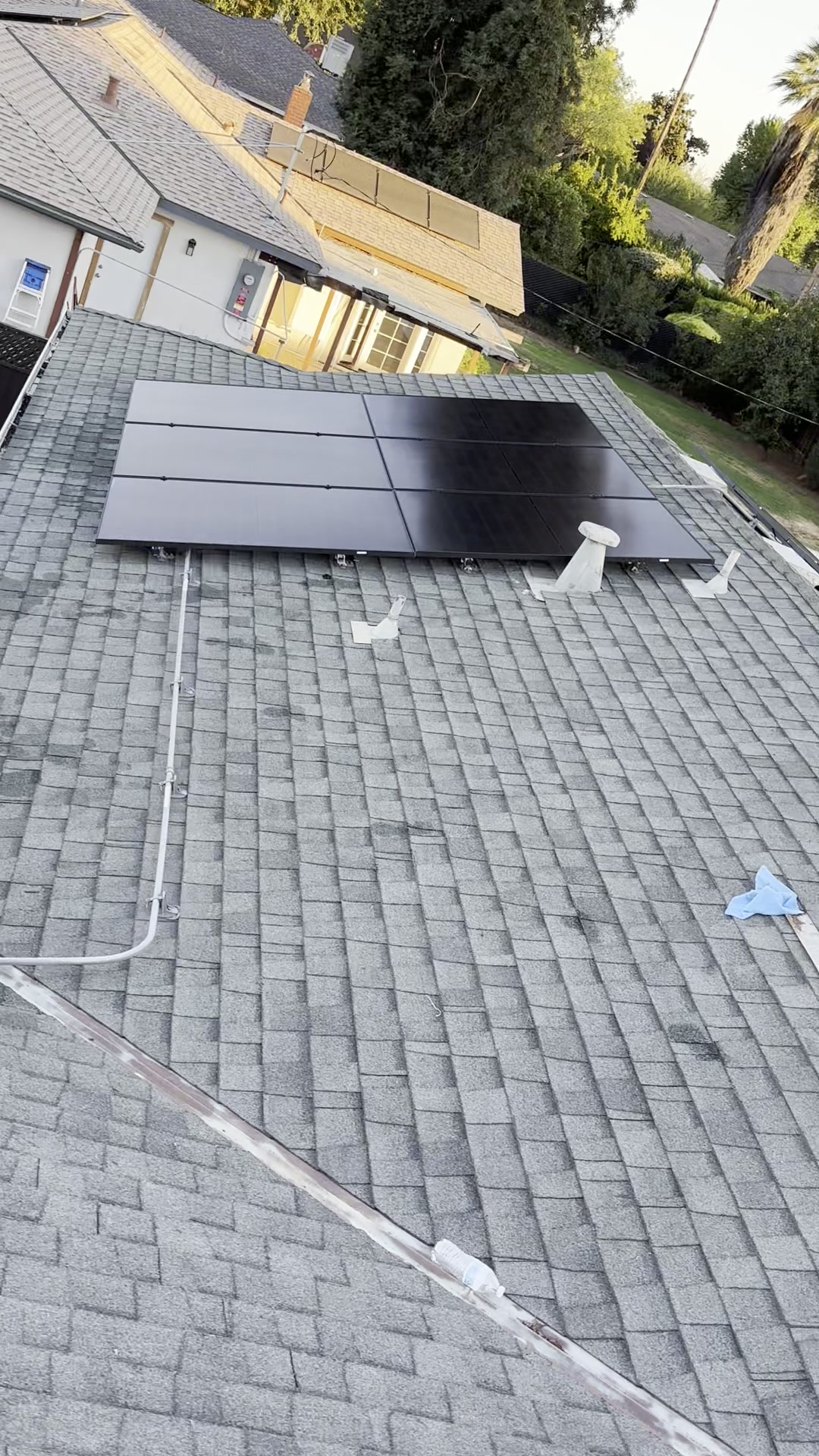 Wide overhead view of a freshly cleaned rooftop solar array above a tidy residential home and backyard.