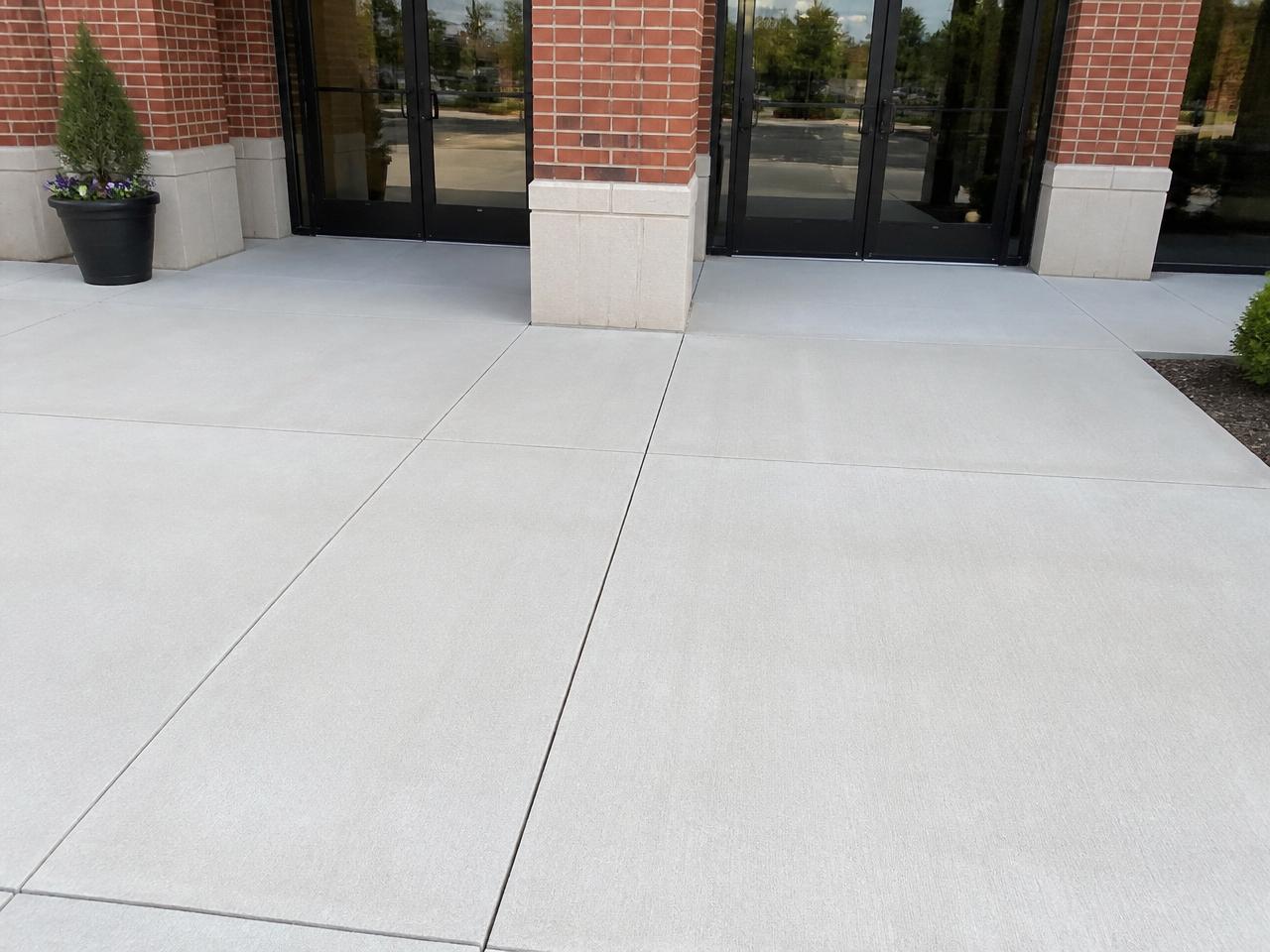 The same retail storefront concrete entryway cleaned to a bright, spotless finish after pressure washing.