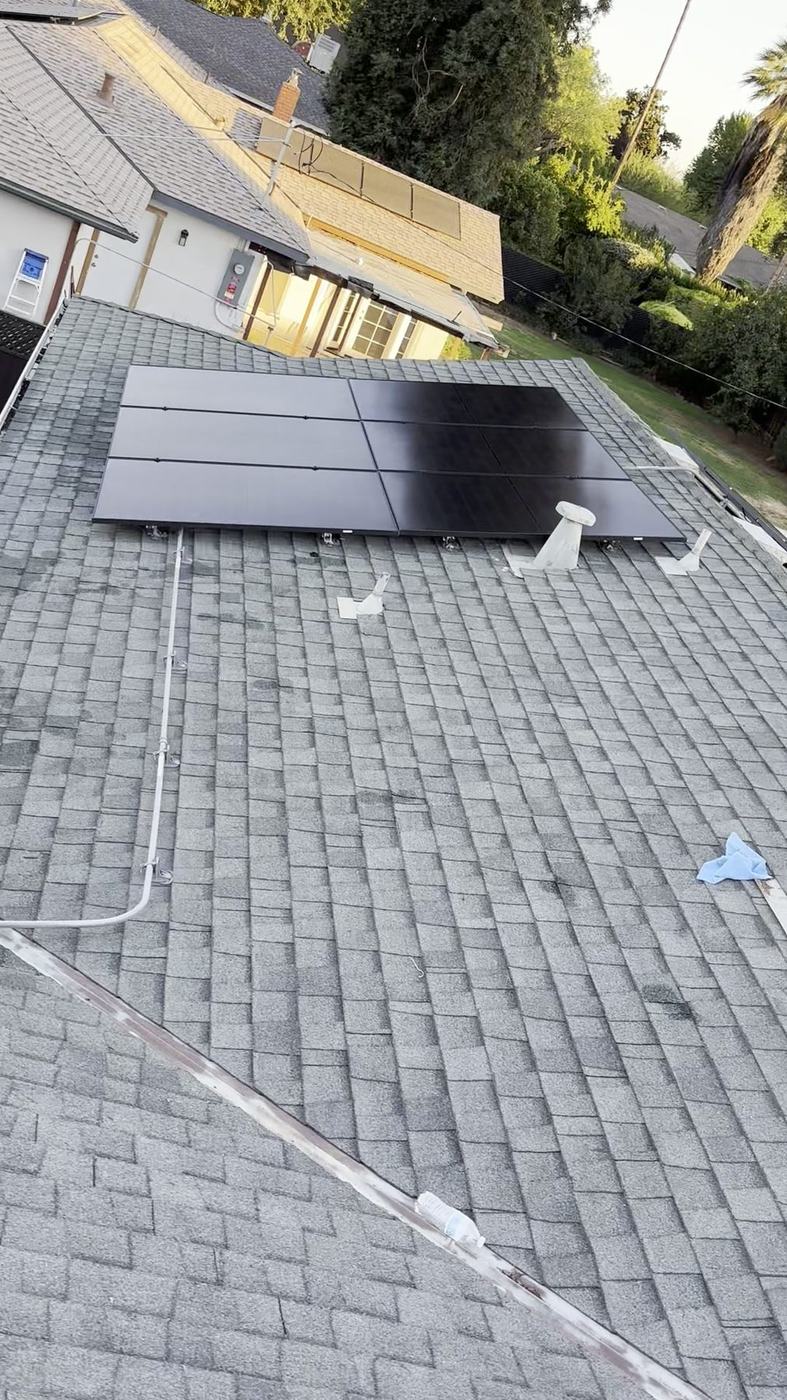 Wide overhead view of a freshly cleaned rooftop solar array above a tidy residential home and backyard.