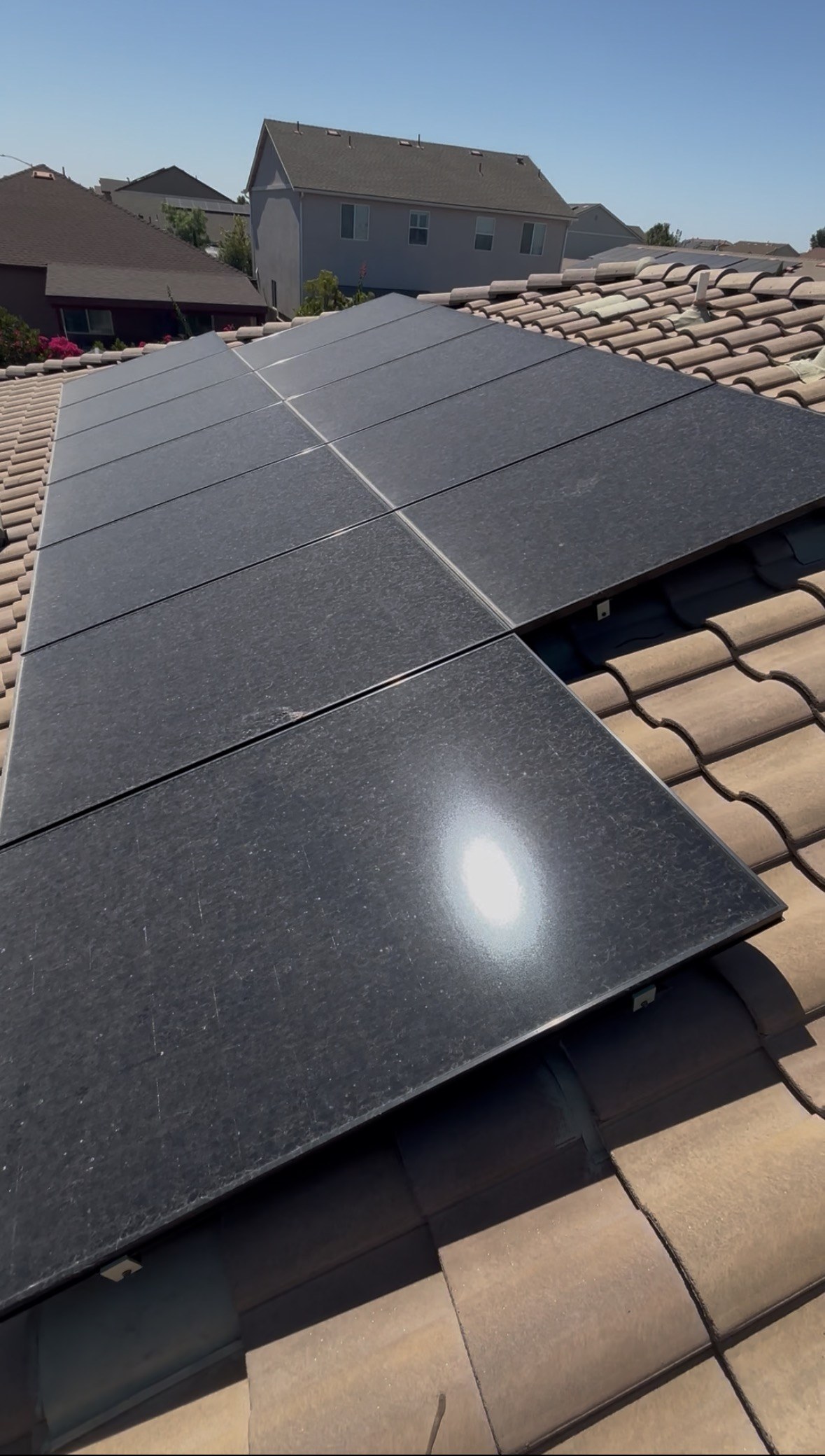 Close-up of clean, streak-free black solar panels on a tile-roof home after cleaning.